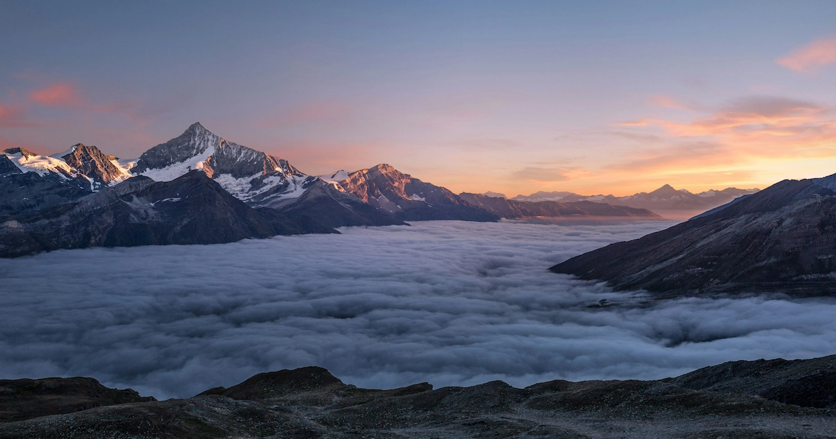 Snow-capped mountains in a sea of clouds at sunset